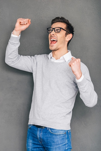 Happy winner. Cheerful young man gesturing and keeping his mouth open while standing 