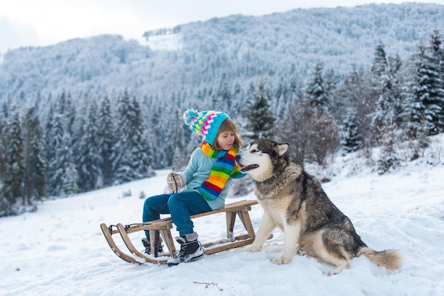 Happy winter child boy dog alaskan malamute and kid in snow winter austria or canada