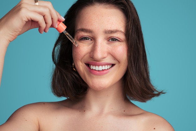 Photo happy woman applying serum on cheek