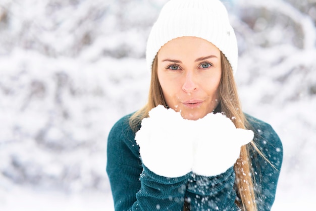 Happy woman on the background of the forest snow falls on the girl the female smiles in winter