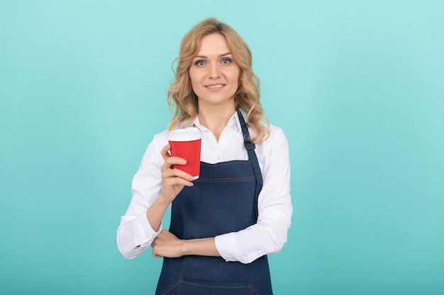 Happy woman barista in cook apron drink takeaway coffee, morning.