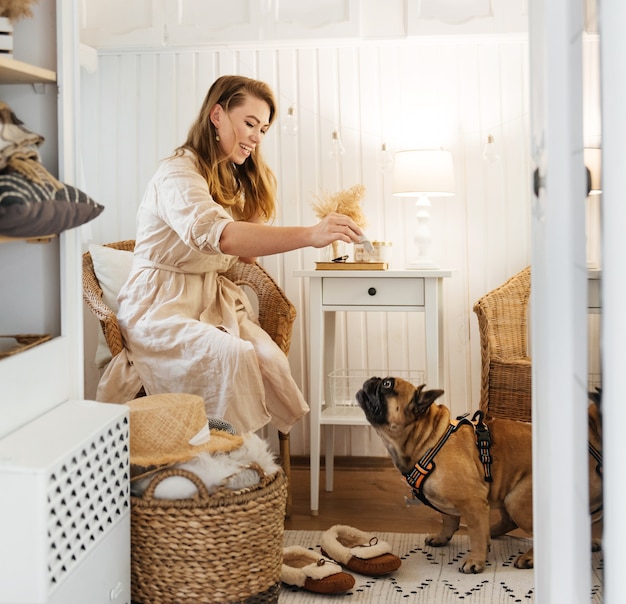 Happy woman in bedroom playing with dog