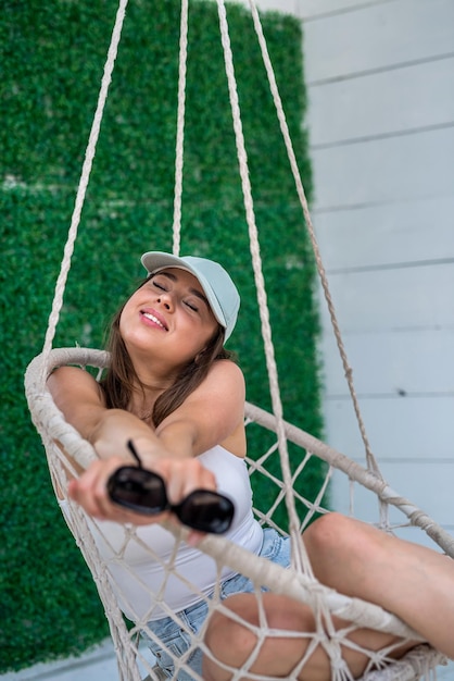 Happy woman in casual cloth and sunglasses relaxing on rocking chair