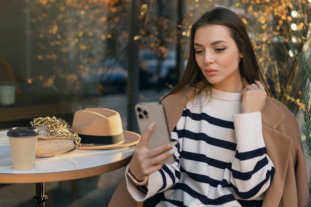 Happy woman in casual wear smiling talking walking drinking coffee chatting online taking selfie using mobile phone alone