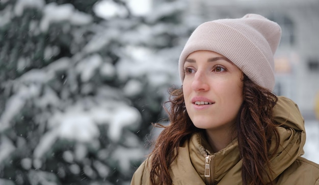 Happy woman catching snowflakes in the city in winter