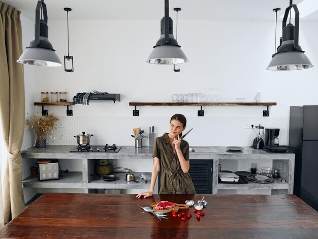 Photo happy woman chef standing in stylish minimalist kitchen interior with natural elements in wood and