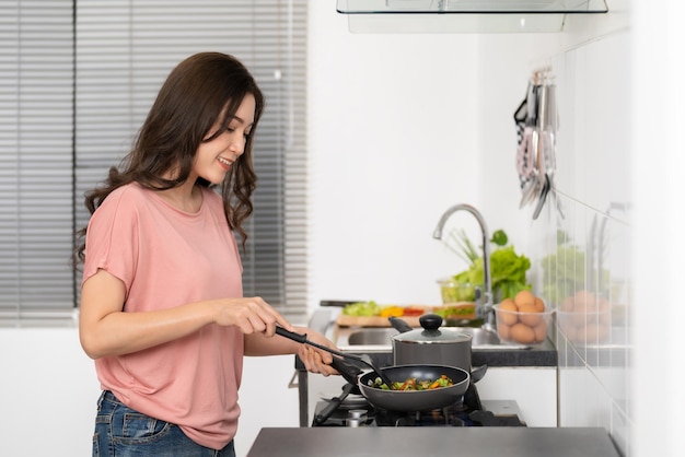 Happy woman cooking and preparing food in the kitchen at home