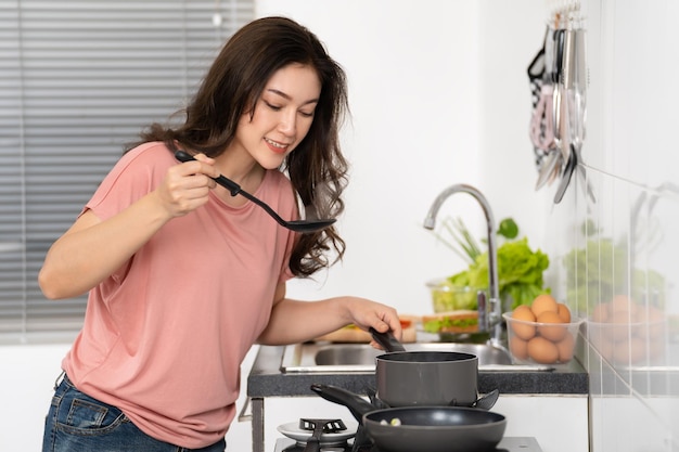 Happy woman cooking and preparing food in the kitchen at home