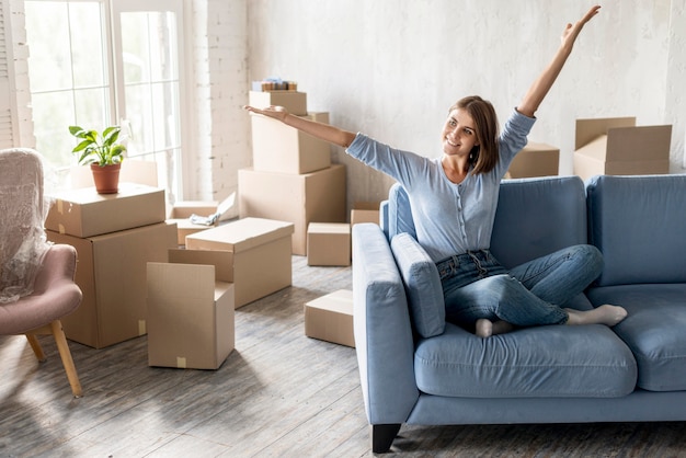 Photo happy woman on the couch moving out with boxes ready