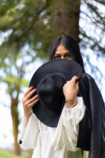 Happy woman covering her face with a hat in the nature vertical portrait