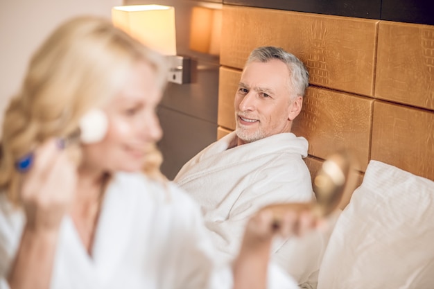 A happy woman. Cute blonde woman doing make up and looking happy