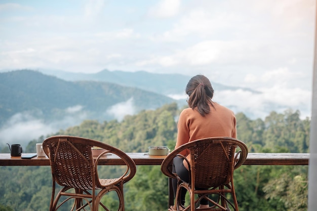 Happy woman drinking coffee and eating breakfast against mountain view at countryside home or homestay in the morning Vacation blogger SoloTravel journey trip and relaxing concept