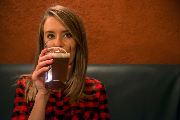 Happy woman drinking light lager beer in pab and looking. Vintage portrait