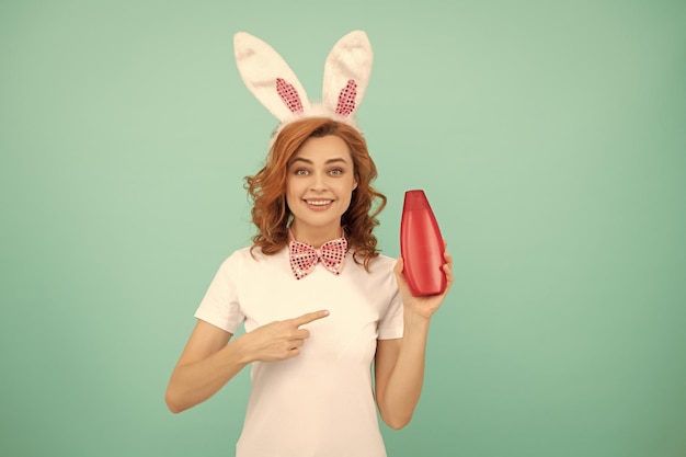 Happy woman in easter bunny ears point finger on shampoo