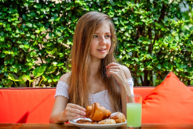 Happy woman eat sweet breakfast or lunch in outdoor restaurant fresh pastry