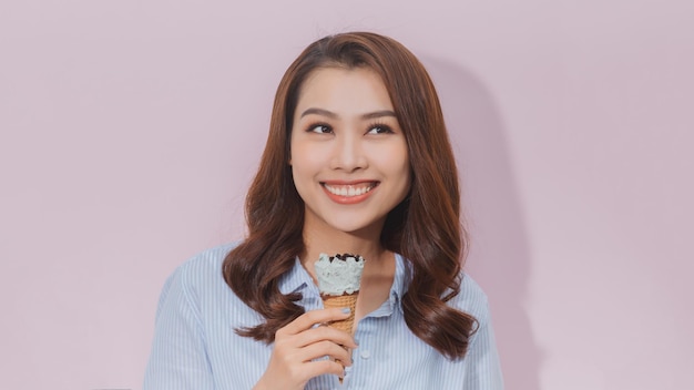 Happy woman eating ice cream, isolated on pink