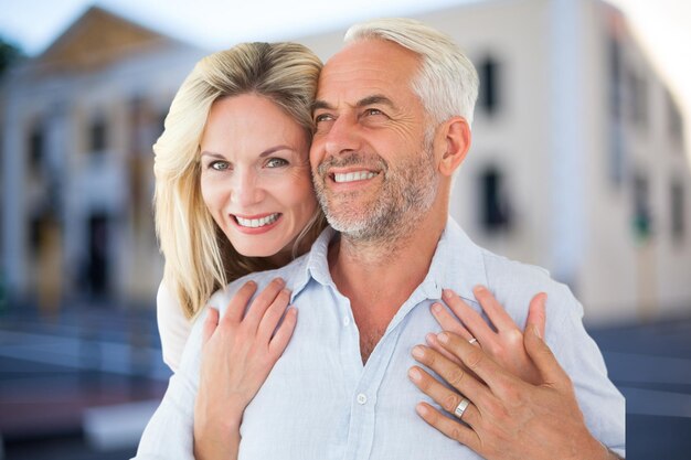 Happy woman embracing man against house