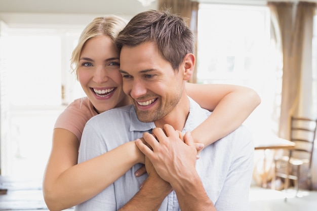 Happy woman embracing man from behind at home