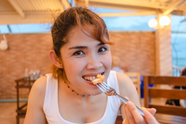 Happy woman enjoy eating squid seafood in the summer vacation