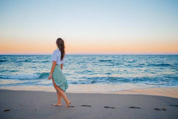 Happy woman enjoying beautiful sunset on the beach