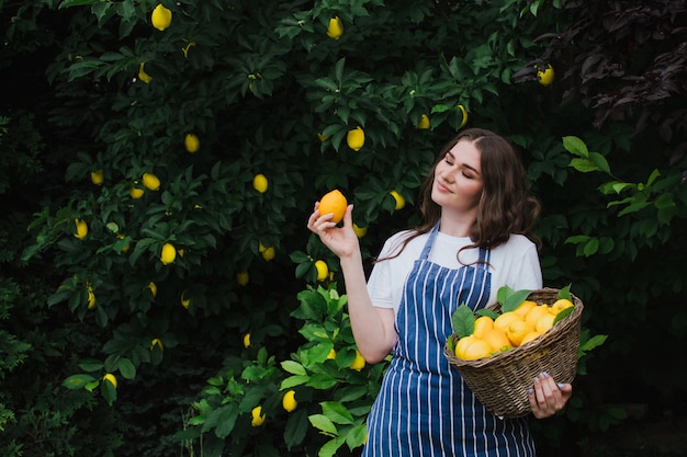 Happy woman gardener picks lemons in the garden and closed her eyes with pleasure