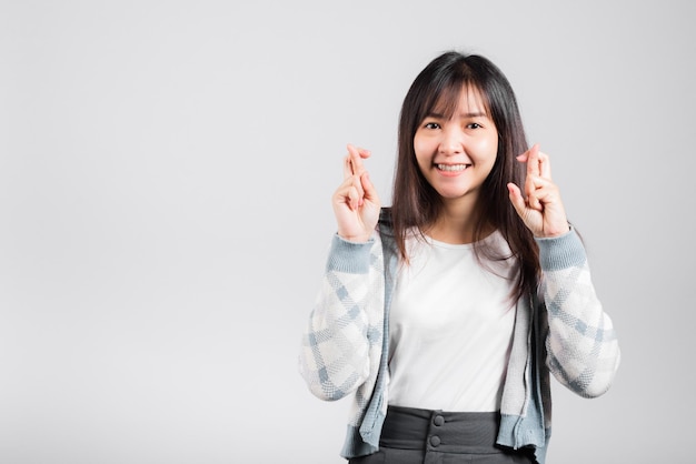 Happy woman have superstition her holding fingers crossed for good luck gesture, Asian beautiful young female smiling superstition, studio shot isolated on white background with copy space