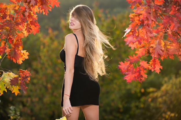 Happy woman holding autumn leafs on face in fall nature portrait of young woman with autumn maple le