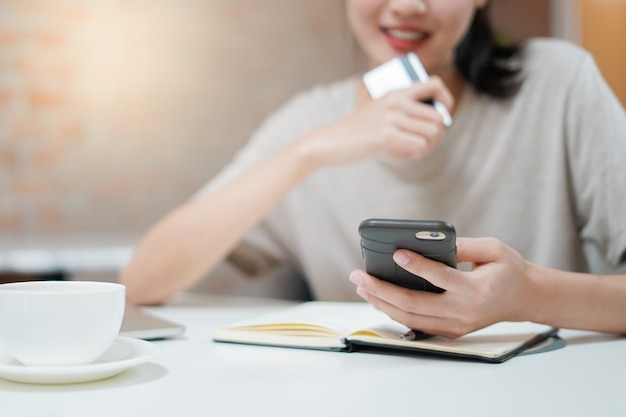 Happy woman holding credit card and using smartphone to shop online