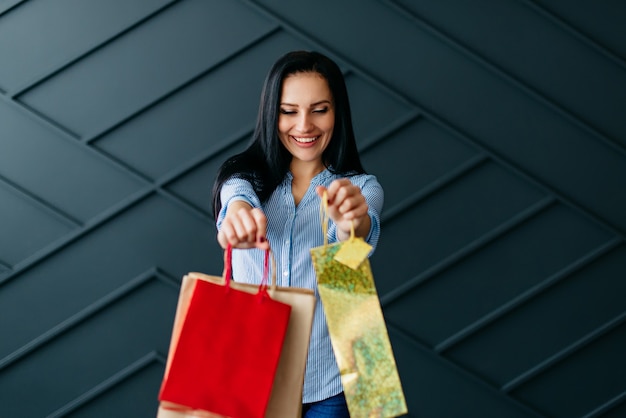 Happy woman holding shopping bags in hands on black background