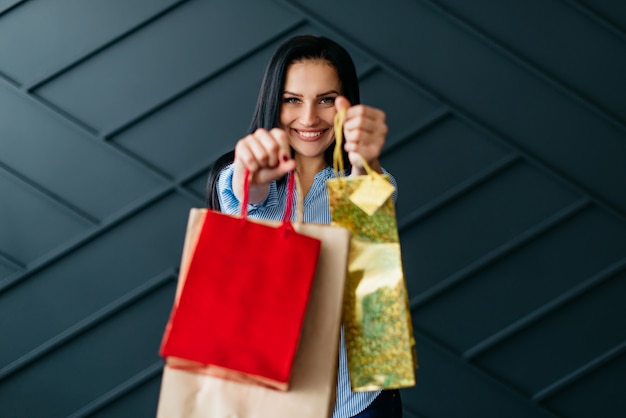 Happy woman holding shopping bags in hands on black background