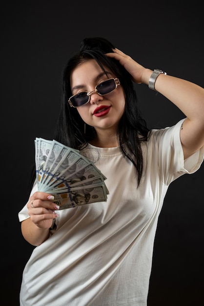 Happy woman holding a whole pile of dollar money cash isolated on black