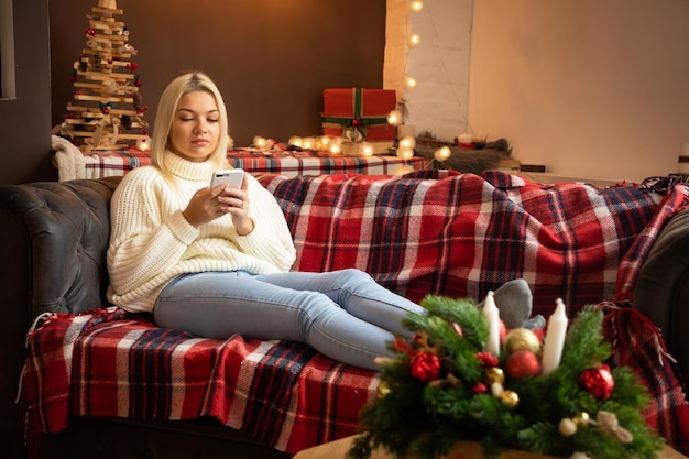 Happy woman at home reading a text message while sitting on sofa in christmas holiday happy new year