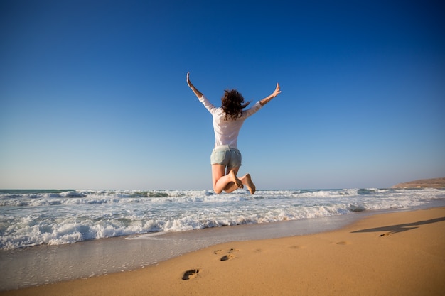 Happy woman jumping at the beach 