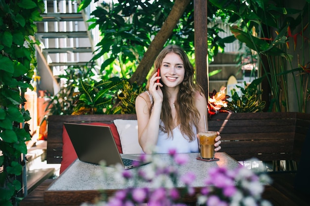 Happy woman looking at camera while talking on phone