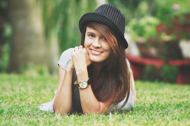 Happy woman lying on the grass with hat