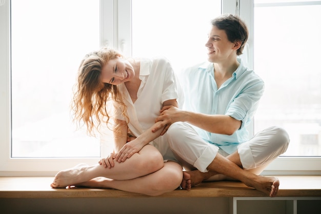 Happy woman and man hugging near window in home on Valentine Day