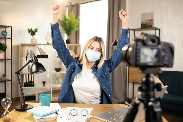 Happy woman in mask talking showing sign OK on camera