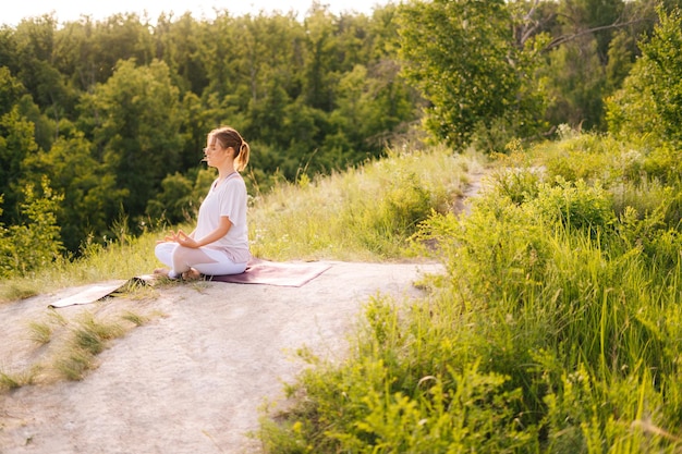 Happy woman meditating sitting in lotus pose with closed eyes holding hand in Om position on knee