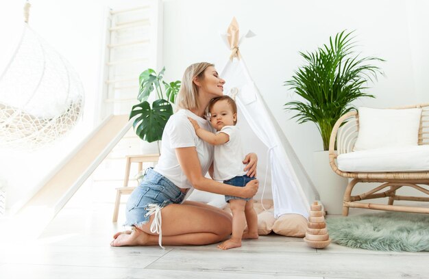 Happy woman mom and her little daughter at home in Childrens room with wigwam Maternal care concept Spend time together Loving family