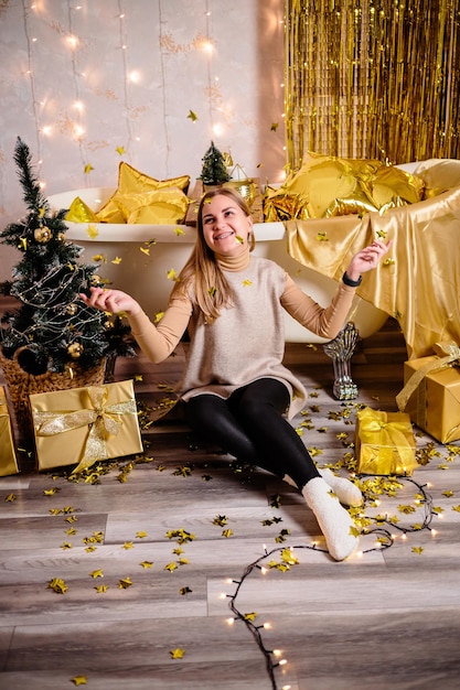 Happy woman in New Year's room New Year's decoration of the room in golden color The concept of the holiday and festive design Home decor for the New Year