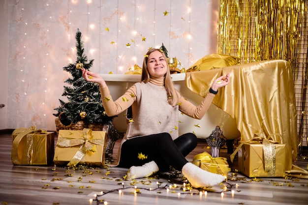 Happy woman in New Year's room New Year's decoration of the room in golden color The concept of the holiday and festive design Home decor for the New Year