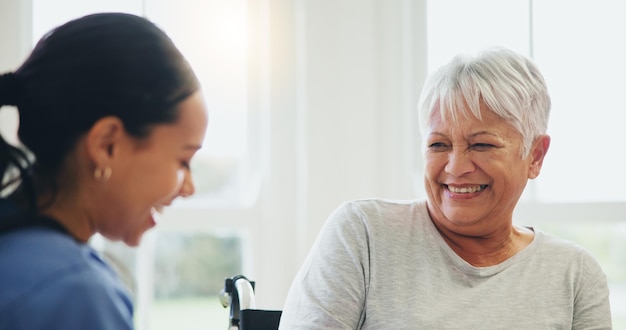 Happy woman nurse and senior patient laughing in elderly care for funny joke humor or consultation at old age home Doctor or medical caregiver smile and laugh with mature person with a disability