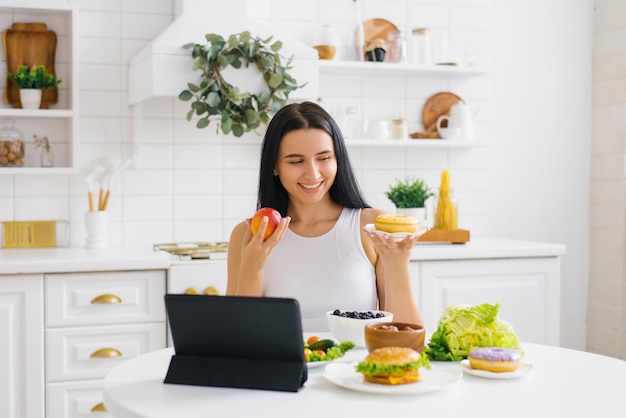 Happy woman nutritionist holds an online lesson or conference in the kitchen on the topic of healthy eating and weight loss