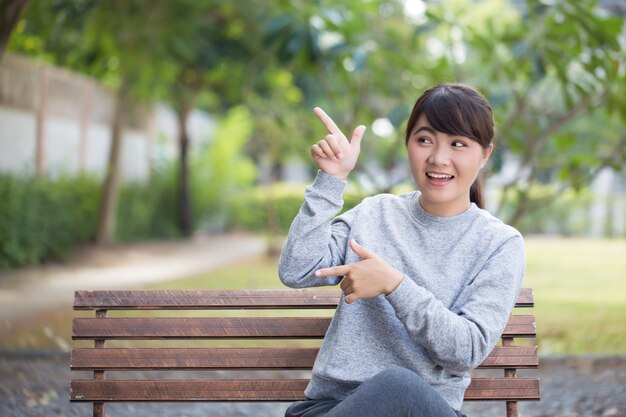 Happy woman at park pointing to copy space