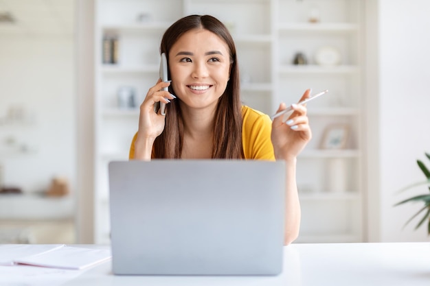 Happy woman on phone with laptop at desk