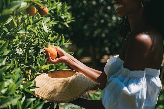 Happy woman picking orange fruit in garden