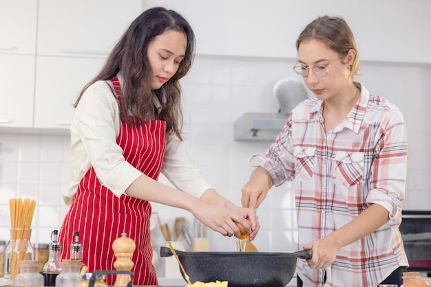 Happy woman preparing food in the kitchen. Woman cracking an egg into a frying pan