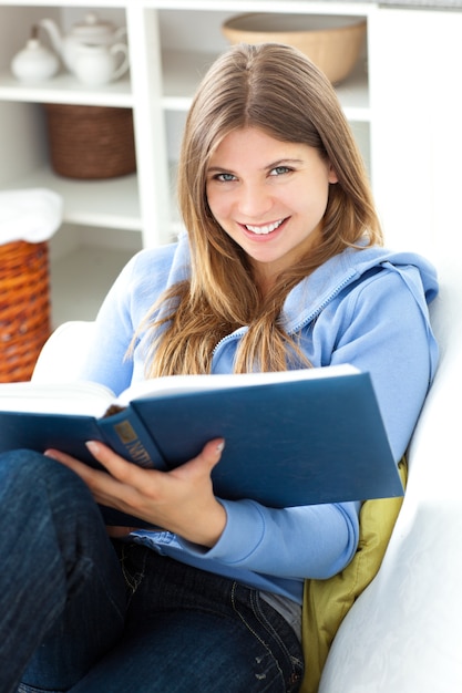 Happy woman reading a book in the living room at home