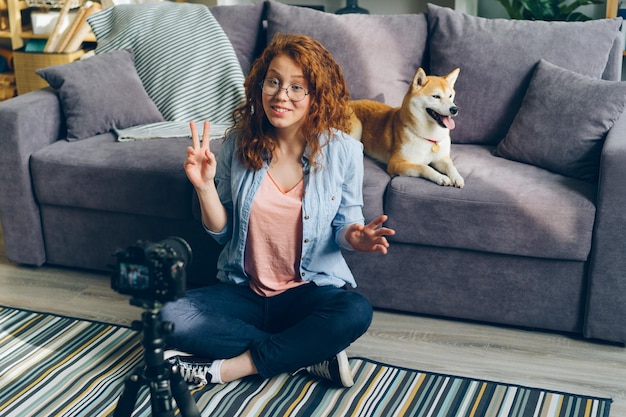 Happy woman recording video about dogs at home using professional camera