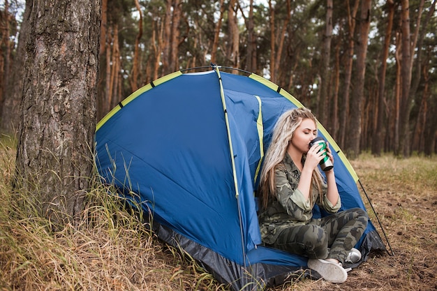 Happy woman relaxation tent concept. Tourism equipment advertisement. Warm with tea.